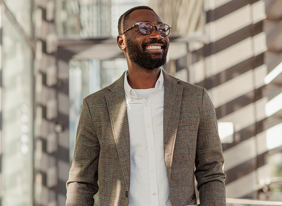 A man with a beard and glasses, smiling while walking outdoors, wearing a suit and white shirt - Fluoride Treatment in Fort Lee, NJ