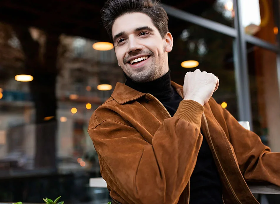 Man with dark hair, wearing a orange jacket, smiling - TMD Treatment in Fort Lee, NJ